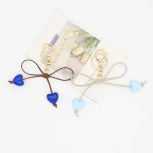 Detailed close-up showing macaron heart bow keychains in brown and beige color options.