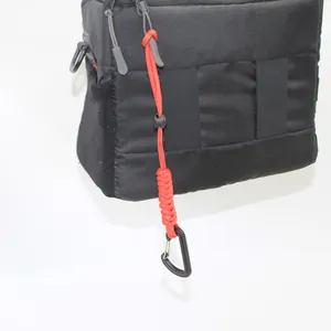 Detail view of red tactical paracord lanyard with black carabiner attached to a bag