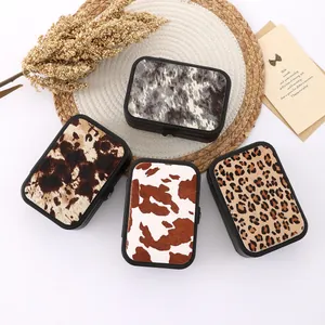 Four animal print jewelry boxes with cow and leopard patterns on a woven mat