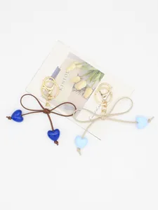 Detail of cute INS style bow keychains with blue heart charms on a decorative card