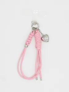 Detail van roze handgevlochten telefoonkoord met hartbedeltje en bevestigingslipje.