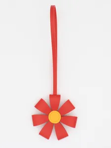 Close-up of a red PU leather flower bag charm with a yellow center on white background