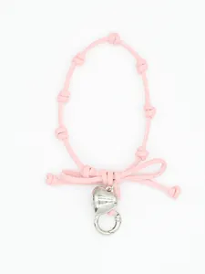 Detail of pink woven wrist strap featuring a silver heart charm and bow knot