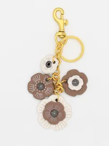 Detalle del llavero retro con flores de camelia en piel sintética y metal dorado.
