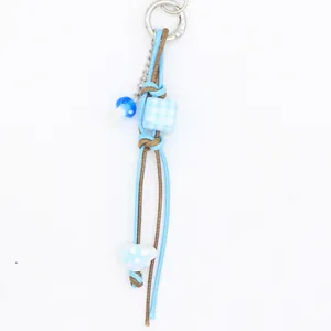 Porte-clés artisanal en cordon de cire bleu avec perle à carreaux et breloque champignon