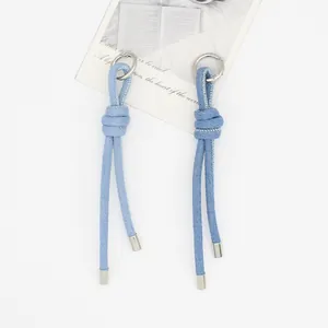 Dettaglio del ciondolo per borsa in denim intrecciato a mano con anello argento.