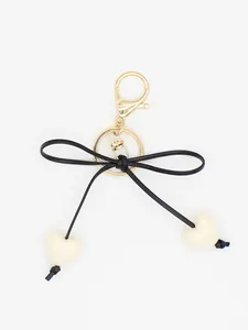 Minimalist black bow keychain featuring cream heart charms for handbags and car keys
