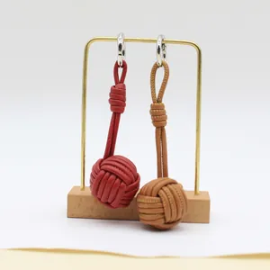 Detailed view of handmade woven leather ball charms in red and tan brown with silver rings