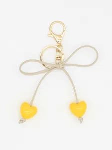 Detailed view of yellow heart charms and beige bow knot on a golden keychain pendant