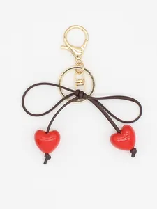 Detailed view of glossy red heart beads and brown bow knot on elegant gold keychain