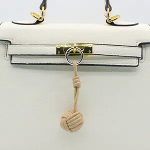 Elegant hand-woven leather ball charm for handbag decoration with gold hardware detail