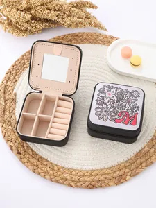 Close-up of portable jewelry box with alphabet M and floral pattern, featuring internal mirror.