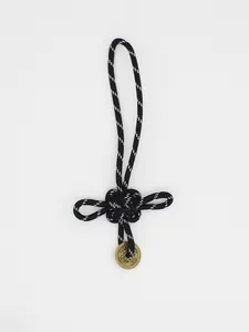 Dettaglio di un nodo cinese portafortuna bianco e nero intrecciato a mano con moneta bronzea.