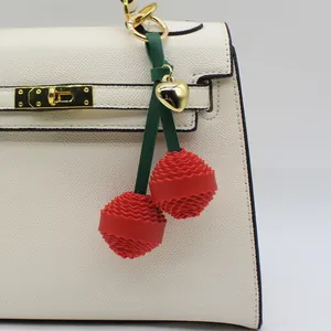 Adorable red 3D cherry bag charm featuring textured petals and a gold heart pendant