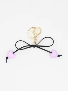 Detailed view of an elegant black bow keychain featuring cute purple macaron hearts