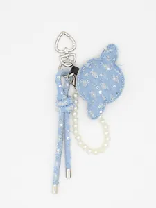Dettaglio di un ciondolo per borsa in denim fatto a mano con catena di perle eleganti.