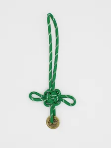 Dettaglio del nodo portafortuna cinese intrecciato verde con moneta di bronzo