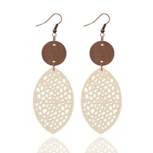 Close-up showing the intricate mesh laser-cut pattern on beige leather and wood earrings