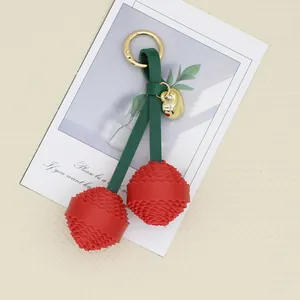 Elegant red PU leather cherry bag charm with layered petals and gold hardware keychain