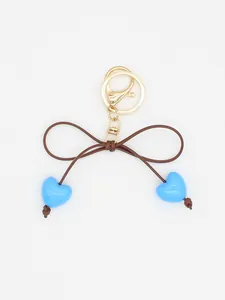 Close-up of a cute blue macaron heart bow keychain with golden clasp and brown cord