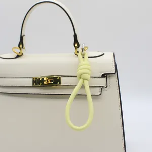 Detail shot of a stylish light yellow PU leather braided knot charm hung on a bag