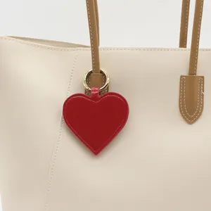 Close-up of a stylish red heart-shaped PU leather magnetic hat clip on a cream tote bag