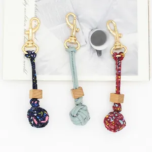 Detailed view of handmade braided ball bag charms with wood beads and gold clasps