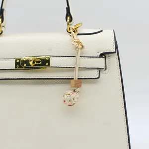 Macro view of a handmade floral fabric braided ball bag charm featuring a natural wood bead.