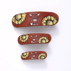 Detail view of vintage hair clip set featuring sunflower and highland cow leather patterns.