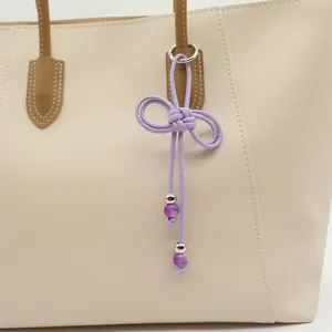 Detailed view of a lavender hand-woven PU cord bow charm with purple beads for bags