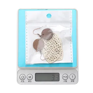 Detailed close-up showing hollowed wood and leather earrings weighing 3.3 grams on a digital scale