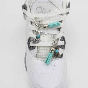 Detailed macro view of ethnic turquoise letter J and L charms with blue tassels on shoes