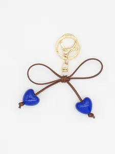 Detail of a cute blue heart and brown bow keychain charm with a gold metal clasp