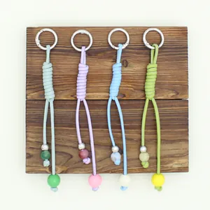 Close-up detail of colorful hand-woven PU cord keychains with beads on wooden background