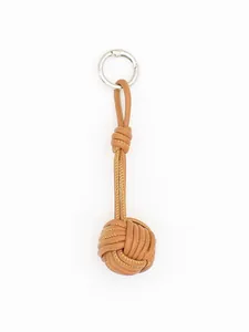 Macro view of a handcrafted brown PU leather woven ball bag charm with silver ring.