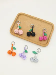 Handmade woven PU cherry charms in six vibrant colors displayed on a wooden tray