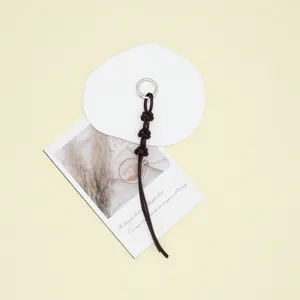 Handmade dark brown braided leather rope keychain charm on a minimalist cream background