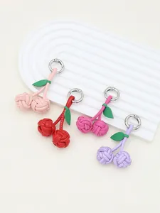 Close-up detail of handmade woven PU cherry bag charms in four vibrant stylish colors