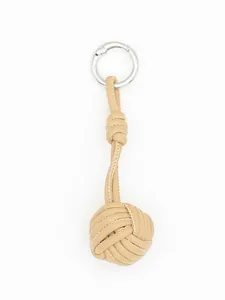 Close-up of handmade woven leather ball bag charm in beige with silver metal ring