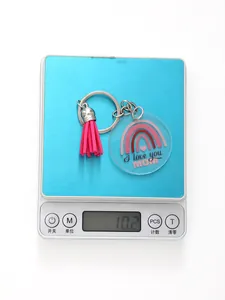 Acrylic keychain with pink tassel and rainbow 'I love you MOM' design on digital scale.