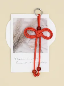 Elegant handmade red woven rope keychain with beads on an aesthetic card display.
