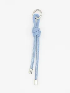 Dettaglio di un ciondolo per borsa in corda di denim intrecciata blu con punte metalliche