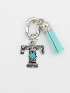 Detailed view of ethnic style silver letter T charm with turquoise stone and blue tassel