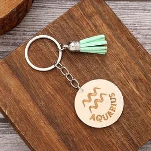Dettaglio di un portachiavi in legno con segno zodiacale Acquario e nappa verde menta