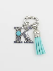 Detail of turquoise letter K keychain with blue tassel and cross engraving