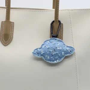 Detailweergave van een blauwe denim Saturnus-sleutelhanger met zilveren lovertjes