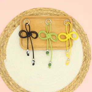 Detail view of handmade braided PU rope keychains in black green and yellow on tray