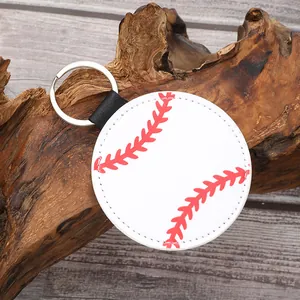 Detail view of a baseball-themed leather keychain with red stitching on a natural wood base.