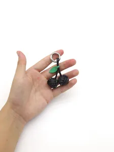 Handheld view showing detail of handmade braided black PU leather cherry bag charm