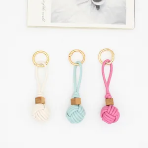 Close-up of hand-woven leather ball bag charms with wooden beads and gold rings